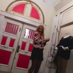 Woman in polka dot dress standing by doors.