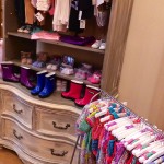 Ornate antique dresser with colorful clothes and boots.