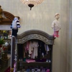 A vintage cabinet with baby clothes and toys.