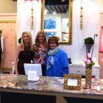 Three women smiling in a boutique store.