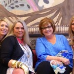 Four women pose in front of artwork.