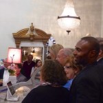 A group of people gather in a room with a chandelier.