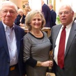 Three people in suits smiling for photo.