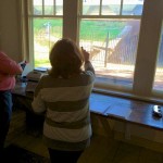 Two people standing by a window with papers.