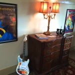 Guitar, dresser, and framed artwork in a room.