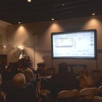 A man presents to an audience in a room.