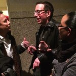 Three people talking and holding drinks.