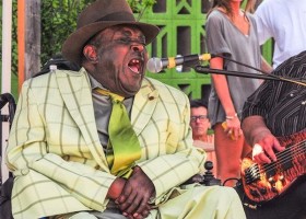 Man in a wheelchair singing into a microphone.