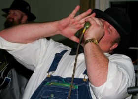 Man in overalls singing into microphone.