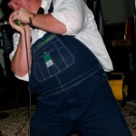 Man in overalls singing into a microphone.