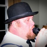 Man in a bowler hat singing into a microphone.