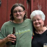 Two people smiling, one holding a beer.