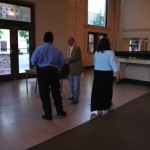 Three people standing in a room with a counter.