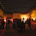 People gather in a dimly lit warehouse.