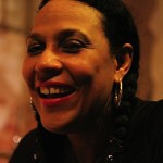 Woman with dark hair and earrings smiling.