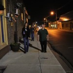 Two people walking at night on a street.