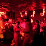 Partygoers in a dimly lit bar with neon signs.