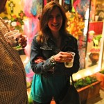 Woman in a denim jacket holding a drink.