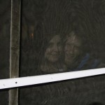 Couple smiling through a window screen.