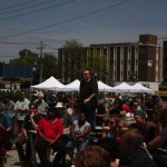 Crowd gathers under tents at outdoor event.