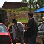 Two men standing by a red car.