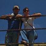 Two people smiling by a fence.