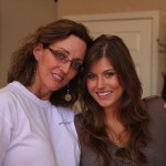 Two women smiling, one with glasses and earrings.