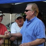 Three men smiling under a blue canopy.