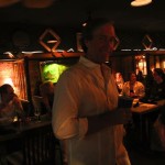 Man smiling in bar with group of people.