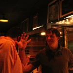 Two men talking in a dimly lit bar.