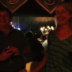 Two people holding drinks in a dimly lit room.