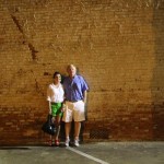 Couple standing in front of a brick wall.