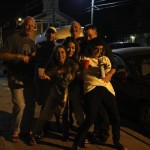 Group of friends standing by a car at night.