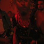 Woman with long hair playing guitar in dark room.