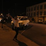 Woman posing with van in front of building.