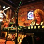 A woman playing a Kurzweil keyboard on stage.