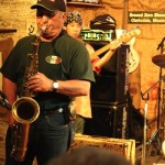 Man playing saxophone on stage at a blues club.