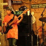 A woman plays a bass guitar at a blues club.