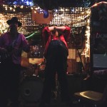 Two men playing music in a dimly lit room.