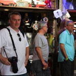 Three men standing in a bar, one with a camera.