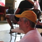 Man in yellow cap sitting at a table.