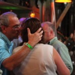 Man with a green bracelet hugs a woman.