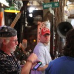 Three men standing outdoors with one using a phone.