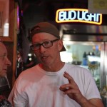 Man smiling in front of a Bud Light sign.