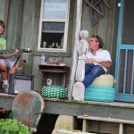 Two people on a porch, one playing guitar.