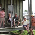 Four people relaxing on a porch with drinks.