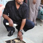 Man in black shirt looking at plaque.