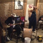 Man plays guitar at a bar with friends.