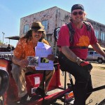 Two men riding a motorized bicycle.