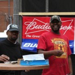 Two men smiling, one holding a drink.